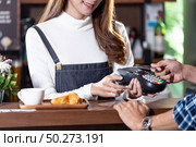 Asian customer using contactless credit card nfs technology pay to barista at cafe bar. Contactless payment preventing from coronavirus covid-19 Spreading and infection, Panoramic web banner crop. Стоковое фото, агентство Ingram Publishing / Фотобанк Лори