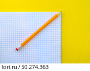 White notebook in a cage and a pencil on a yellow background. Стоковое фото, фотограф Юлия Николаева / Фотобанк Лори