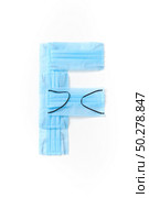 Capital letter F handmade from medical antibacterial protective blue face masks on a white background, copy space. Creative alphabet for making up new words.. Letter F made from protective medical masks on a white background. Стоковое фото, агентство Ingram Publishing / Фотобанк Лори