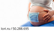 Medical mask on the belly of pregnant woman. Child protection. Concept of coronavirus, covid quarantine. Pregnant woman use face mask covering on her abdomen for protecting fetus or baby. Banner 2:1. Стоковое фото, фотограф Марина Демидюк / Фотобанк Лори