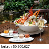 Bowl of gourmet fresh seafood on ice with savory sauce serve with white wine glass on vintage wooden table. Restaurant gastronomy food and drink consumerism concept. Стоковое фото, агентство Ingram Publishing / Фотобанк Лори