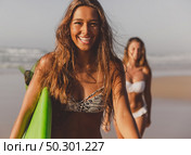 Best friends enjoying the summer, running on the beach with a surfboard. Стоковое фото, агентство Ingram Publishing / Фотобанк Лори