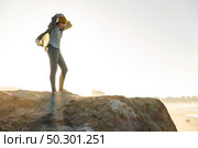 Beautiful woman with a yellow cap on a cliff over the beach. Стоковое фото, агентство Ingram Publishing / Фотобанк Лори