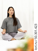 Asian Woman do meditate to relax and reduce stress and strain for good mental health cause from city lockdown from coronavirus COVID-19 Pandemic. Meditation relax and leisure activity concept. Стоковое фото, агентство Ingram Publishing / Фотобанк Лори