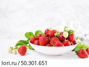 Strawberry on plate with twigs and leaves on white  background. Стоковое фото, агентство Ingram Publishing / Фотобанк Лори