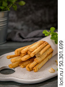 Fresh baked homemade grissini bread sticks in white ceramic tray with olive oil and basil herbs over kitchen counter top. Стоковое фото, агентство Ingram Publishing / Фотобанк Лори