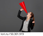 Business young woman speaking to a megaphone, over a grey background. Стоковое фото, агентство Ingram Publishing / Фотобанк Лори