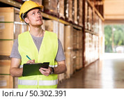 Portrait white caucasian warehouse worker stand with archboard and pen for inventory checking in large warehouse distribution center. Reopening traditonal business warehouse and logistic concept. Стоковое фото, агентство Ingram Publishing / Фотобанк Лори