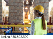 Side view of asian female warehouse worker with archboard flip chart look inventory with dustrubution warehouse in background. Reopening business warehouse technology and logistic concept. Стоковое фото, агентство Ingram Publishing / Фотобанк Лори