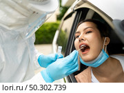Portrait of asian woman drive thru coronavirus covid-19 test by medical staff with PPE suit by throat swab. New normal healthcare drive thru service and medical concept. Стоковое фото, агентство Ingram Publishing / Фотобанк Лори