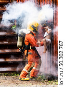 Firefighter rescue girl little child from burning building. He hold the girl and rescue her through window of building. Firefighter safety rescue from accident and public service concept. Стоковое фото, агентство Ingram Publishing / Фотобанк Лори