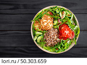 Lunch bowl with buckwheat porridge, fried chicken cutlets and fresh vegetable salad of arugula, lettuce, chard leaves, tomato, cucumber and flax seeds. Стоковое фото, агентство Ingram Publishing / Фотобанк Лори