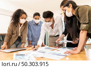 Interracial asian business team brainstorming idea at office meeting room after reopen due to coronavirus COVID-19 city lockdown. They wear face mask reduce risk to infection as new normal lifestyle. Стоковое фото, агентство Ingram Publishing / Фотобанк Лори