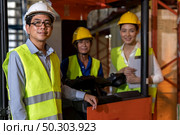 Portrait of Asian warehouse manager and his team worker with forklift truck in background. Reopening business warehouse inventory technology and logistic concept. Стоковое фото, агентство Ingram Publishing / Фотобанк Лори