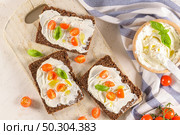 Rye bread bruschetta with cream cheese, olive oil and basil dip, cherry tomatoes, fresh basil leaves on wooden board. Стоковое фото, агентство Ingram Publishing / Фотобанк Лори
