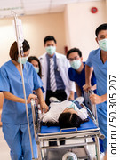 Seriously injured patient with oxygen mask on gurney stretcher bed pushed by medical team of doctor nurse and paramedic to the Operating Room. Emergency health care and medical hospital concept. Стоковое фото, агентство Ingram Publishing / Фотобанк Лори