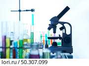 Laboratory interior: test tubes and flasks with colorful liquids, modern microscope standing on bench, no people. Стоковое фото, агентство Ingram Publishing / Фотобанк Лори