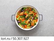 Chicken drumsticks roasted with vegetables in cast iron pan on kitchen table, top down view. Стоковое фото, агентство Ingram Publishing / Фотобанк Лори