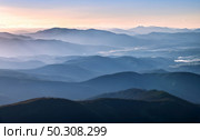 Mountains lighted by bright sunbeams at sunset in autumn. Landscape with mountain ridges in fog, rocks, forest, colorful sky with orange sunlight in fall. Aerial view of mountain valley. Top view. Стоковое фото, агентство Ingram Publishing / Фотобанк Лори