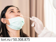 Medical staff with PPE suit test coronavirus covid-19 to asian woman by nose swab at hospital. COVID-19 testing health care concept. Стоковое фото, агентство Ingram Publishing / Фотобанк Лори