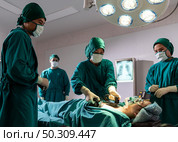 Surgeon doctor and nurse using Defibrillator to patient while patient have problem with Sudden Cardiac Arrest while surgery in Operating Room OR. Medical health care Surgery concept. Стоковое фото, агентство Ingram Publishing / Фотобанк Лори