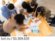 Top View Interracial asian business team brainstorming idea at office meeting room after reopen due to coronavirus COVID-19 city lockdown. They wear face mask as new normal lifestyle. Стоковое фото, агентство Ingram Publishing / Фотобанк Лори