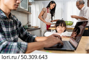 Portrait Asian upset girl waiting her father working from home while city lockdown in dining room while mom and grandfather cooking in kitchen. Domestic life multigenerational family concept. Стоковое фото, агентство Ingram Publishing / Фотобанк Лори
