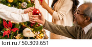 Panoramic Close up hand little asian girl decorate Christmas tree with grandfather prepare for season greeting of Merry Christmas and Happy Holidays. Multigenerational Family engage happiness concept. Стоковое фото, агентство Ingram Publishing / Фотобанк Лори