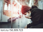 Sick woman in a mask coughing in public during coronavirus pandemic. Стоковое фото, агентство Ingram Publishing / Фотобанк Лори