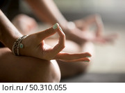 Gyan mudra close up, woman joining together the tip of index finger with thumb, wearing wrist bracelets, practicing yoga in concentration pose, stress relieve exercise at home, focus on right hand. Gyan mudra close up image. Стоковое фото, агентство Ingram Publishing / Фотобанк Лори