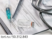 A closeup of an ampoule and a needle syringe on a document with a phonendoscope on the background. Closeup of an ampoule and a needle syringe on a document with a phonendoscope on the background. Стоковое фото, агентство Ingram Publishing / Фотобанк Лори