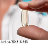 Health professional demonstrating a nutritional supplement capsule in a clinical setting. Стоковое фото, фотограф Климов Денис / Фотобанк Лори