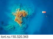 Boat on blue sea at sunset in summer. Aerial view of motorboat on sea bay, rocks and stones in clear azure water. Tropical landscape with yacht and swimming people. Top view. Oludeniz, Turkey. Travel. Стоковое фото, агентство Ingram Publishing / Фотобанк Лори