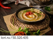 Delicious hummus in ceramic bowl. Colorful snack composition on a black wooden background. Стоковое фото, агентство Ingram Publishing / Фотобанк Лори