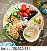 Chicken breast grilled with fresh vegetables, olives, feta cheese, flatbread and hummus, top view. Стоковое фото, агентство Ingram Publishing / Фотобанк Лори