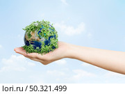 Sustainable living environmentalist hand holding green earth. Стоковое фото, агентство Ingram Publishing / Фотобанк Лори