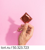 close up man holding up red condom. Стоковое фото, агентство Ingram Publishing / Фотобанк Лори