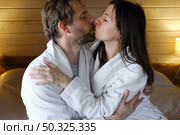Mature couple in a white bathrobes hugging each other kissing at home bedroom. Intimate Moment. Tender embrace shared between a loving middle age man and woman, husband and wife. Deep love. Vacation. Стоковое фото, фотограф Марина Демидюк / Фотобанк Лори