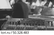 A sound control panel in the foreground and a blurred musician in the background. The shot conveys a vivid musical atmosphere. Close-up of a music mixer during studio work. Стоковое видео, видеограф Воловодов Владимир / Фотобанк Лори
