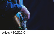 Bass guitar playing with fingers on black background. Close-up. The bass guitar has 5 strings and a stylish wooden deck. Recording in the studio. Стоковое видео, видеограф Воловодов Владимир / Фотобанк Лори