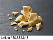 From above of fresh pure raw butter of Theobroma cocoa placed on texture gray surface. Rough pieces of organic cocoa butter. Стоковое фото, агентство Ingram Publishing / Фотобанк Лори