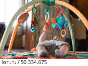 baby lying developing rug with mobile educational toys. Стоковое фото, агентство Ingram Publishing / Фотобанк Лори