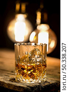 Glass of whiskey lighting with edison lamps. Стоковое фото, агентство Ingram Publishing / Фотобанк Лори