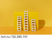 ladders arrangement with yellow background. Стоковое фото, агентство Ingram Publishing / Фотобанк Лори
