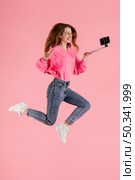 portrait happy woman jumping with selfie stick. Стоковое фото, агентство Ingram Publishing / Фотобанк Лори