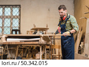 professional carpenter cutting wooden plank with handsaw workshop. Стоковое фото, агентство Ingram Publishing / Фотобанк Лори