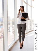 front view businesswoman holding binder talking phone. Стоковое фото, агентство Ingram Publishing / Фотобанк Лори
