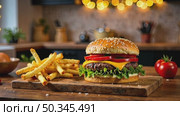 Delicious burger and French fries in home kitchen with Christmas decor, lights of garland. Delivery from fast food restaurant, menu burger home cooking for New year. AI generated; Стоковое AI-видео, аниматор Ольга Симонова / Фотобанк Лори