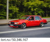 Volvo 740 rushing on the city road. Red old 4-door saloon car moving on the street. Редакционное фото, фотограф Константин Григорьев / Фотобанк Лори