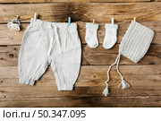 baby s pant socks headwear pacifier hanging clothesline with clothespins against wooden wall. Стоковое фото, агентство Ingram Publishing / Фотобанк Лори